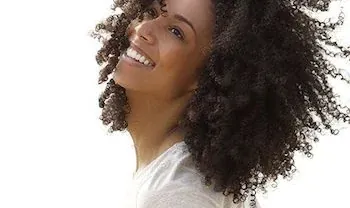 A woman smiling, from the practice's own page on CEREC same-day crowns.