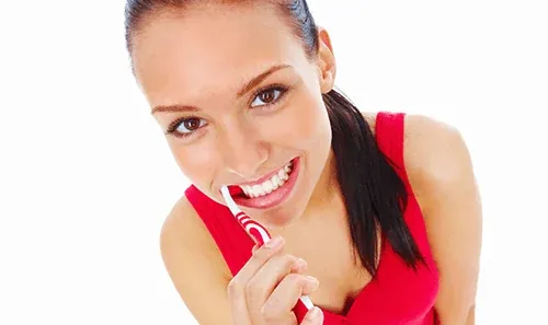 A woman brushing her teeth, illustrating daily dental hygiene.